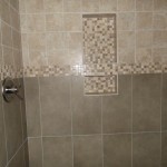 Two shelf shower niche with tumbled mosaic banner running through it