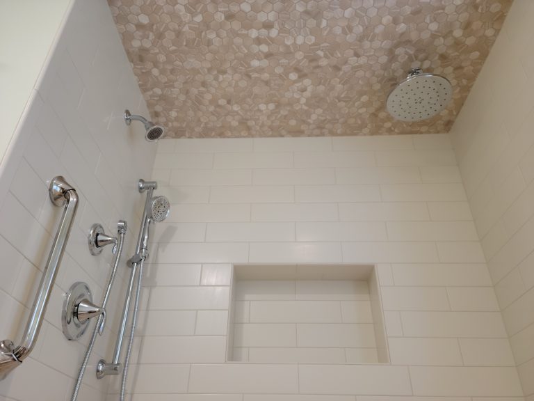 Subway tile shower walls with mosaic accents.