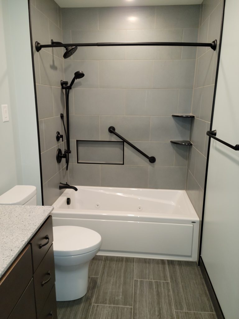New whirlpool tub replacement with tile walls and matte black shower fixtures
