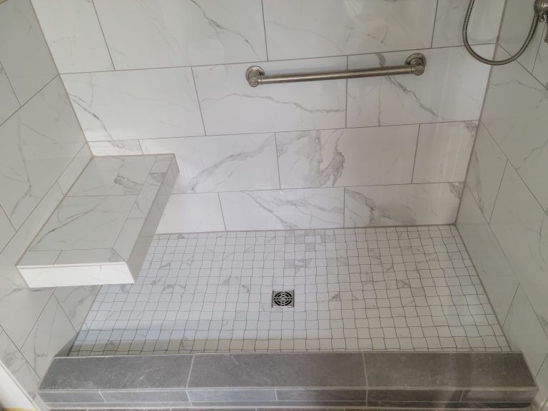Tile shower featuring basket weave floor and floating bench seat.