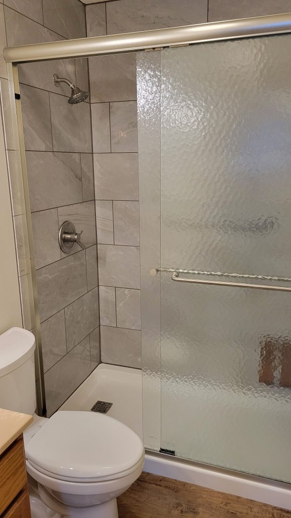 Large format tile shower walls with sliding glass doors